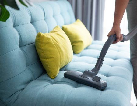 close up of man's hand cleaning couch using vacuum cleaner at home